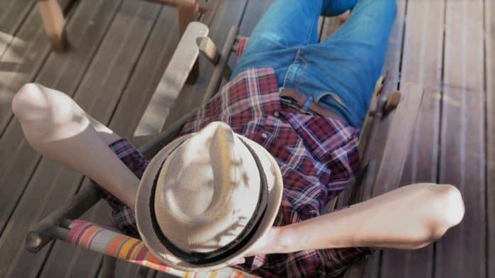 top view on a man wearing hat relaxing on a lounge chair on a wooden terrace