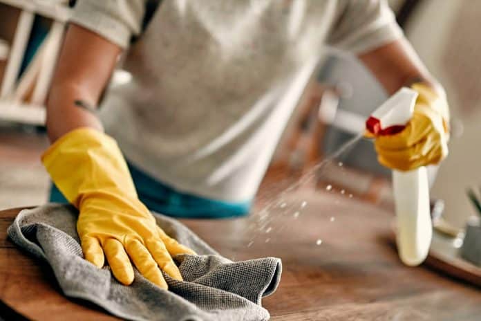 Une personne nettoyant une surface avec des gants jaunes et un spray nettoyant. Une personne nettoyant une surface avec des gants jaunes et un spray nettoyant.