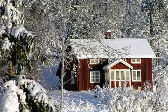 Une maison rouge entourée de neige avec des arbres enneigés. Une maison rouge entourée de neige avec des arbres enneigés.