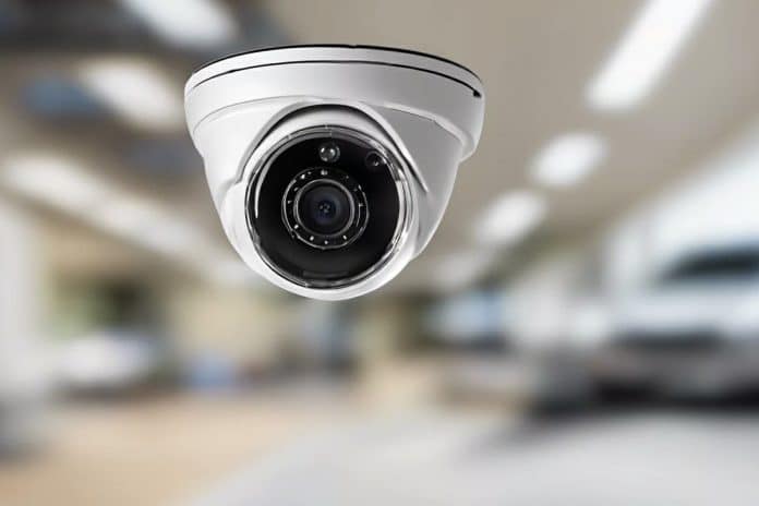 Une caméra de surveillance blanche installée au plafond d'une pièce. Une caméra de surveillance blanche installée au plafond d'une pièce.