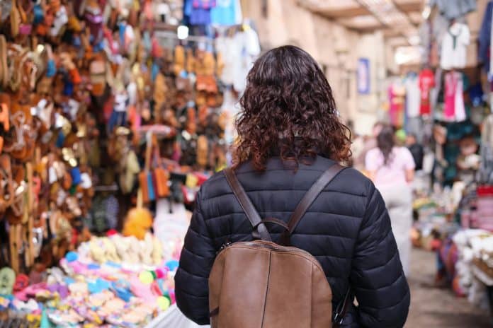 Woman walking through marrakech souk market with backpack Visiter un souk marocain