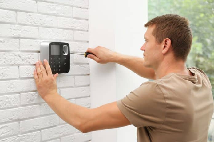 Male technician installing security alarm system indoors Installation de serrure connectée